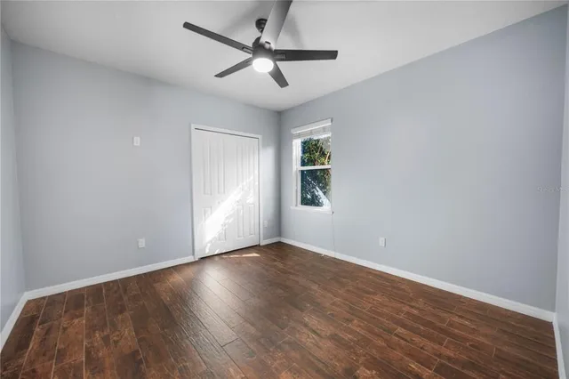 an empty room with wooden floor ceiling fan and windows