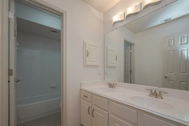 a bathroom with a shower sink vanity and mirror
