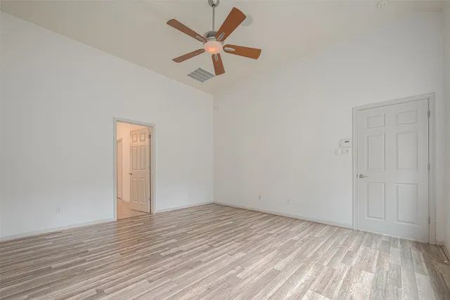 an empty room with wooden floor and a ceiling fan