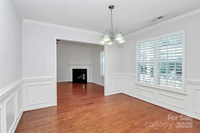 a view of a livingroom with a chandelier fireplace and wooden floor