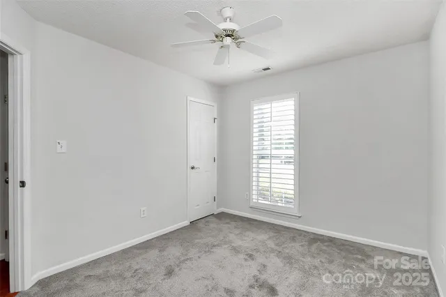 an empty room with windows and chandelier fan