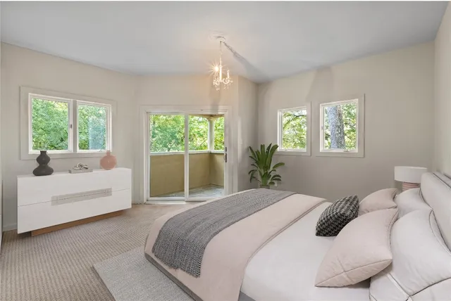 a bedroom with a large white bed couches and white walls