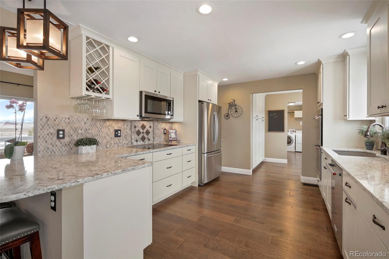 14929 South Spring Valley Road Larkspur, CO 80118 - Photo 11 of 40 a large kitchen with stainless steel appliances granite countertop a lot of counter space and wooden floors