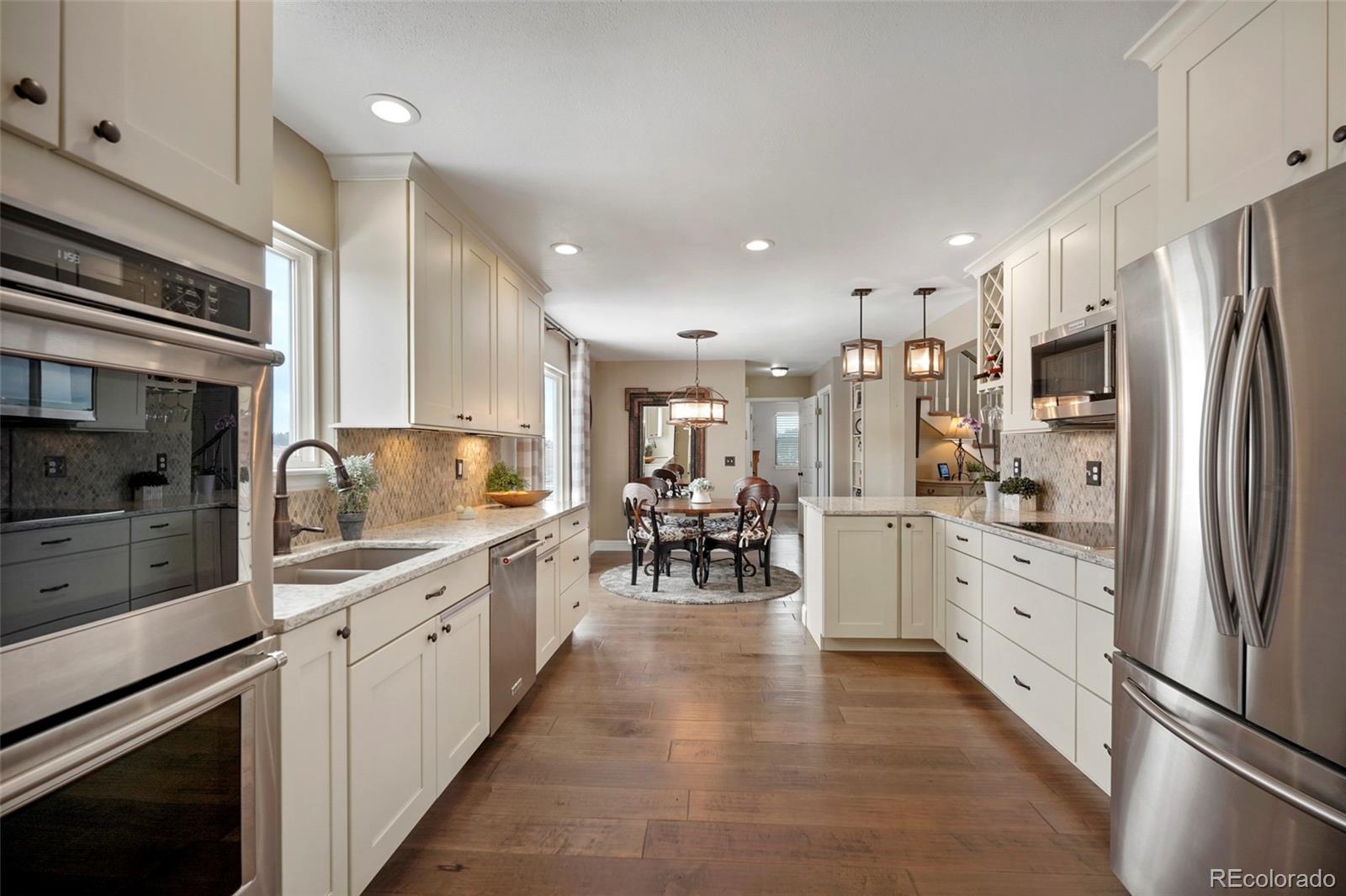 14929 South Spring Valley Road Larkspur, CO 80118 - Photo 12 of 40 a kitchen with white cabinets and stainless steel appliances