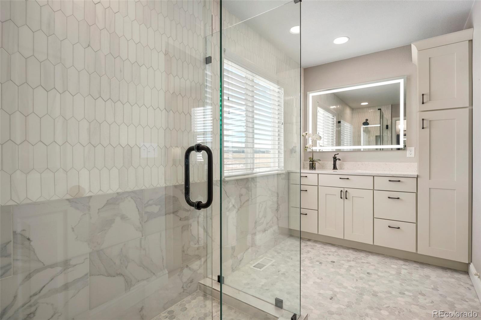 14929 South Spring Valley Road Larkspur, CO 80118 - Photo 18 of 40 a bathroom with a granite countertop sink a mirror and shower