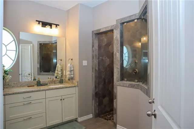 a bathroom with a mirror a double vanity sink and glass door