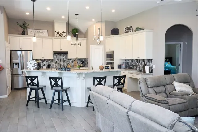 a living room with stainless steel appliances kitchen island granite countertop furniture and a wooden floor