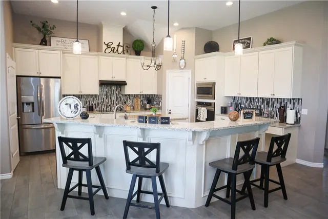 a kitchen with stainless steel appliances kitchen island granite countertop a table chairs and a refrigerator