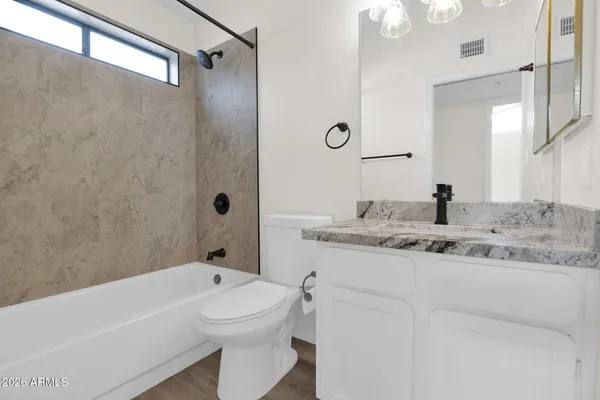 a bathroom with a granite countertop sink a toilet and shower