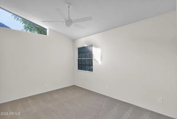 an empty room with a ceiling fan and window