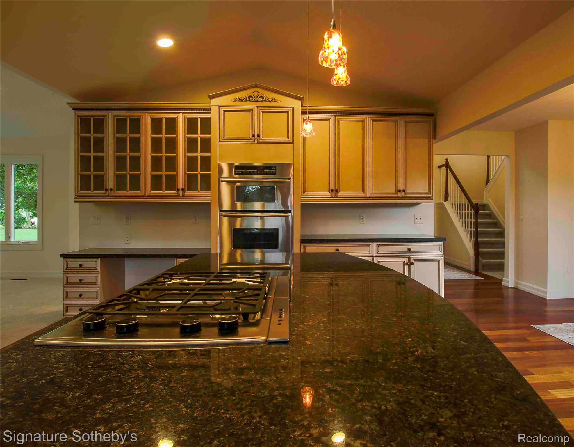 3131 Smugglers Ridge Walled Lake, MI 48390 - Photo 3 of 35 Kitchen featuring a spacious island with a built-in gas cooktop, dark granite countertops, and pendant lighting