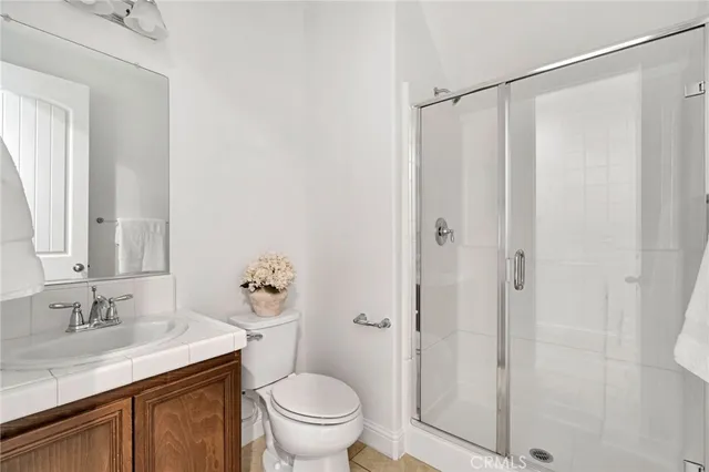 a bathroom with a granite countertop sink toilet a mirror a vanity and shower