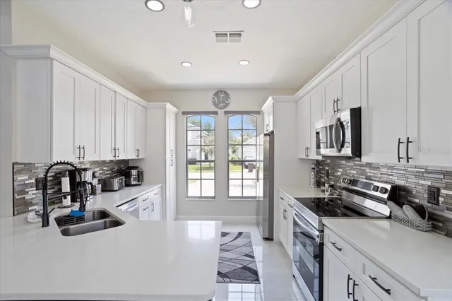 a kitchen with sink a stove and white cabinets