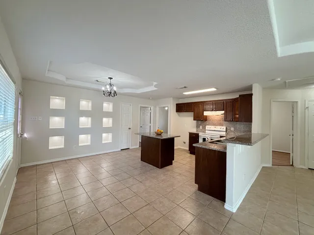 a large kitchen with a stove a sink dishwasher and a refrigerator with wooden floor