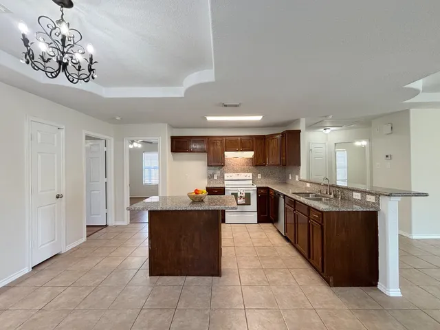 a large kitchen with kitchen island granite countertop a large counter top and stainless steel appliances