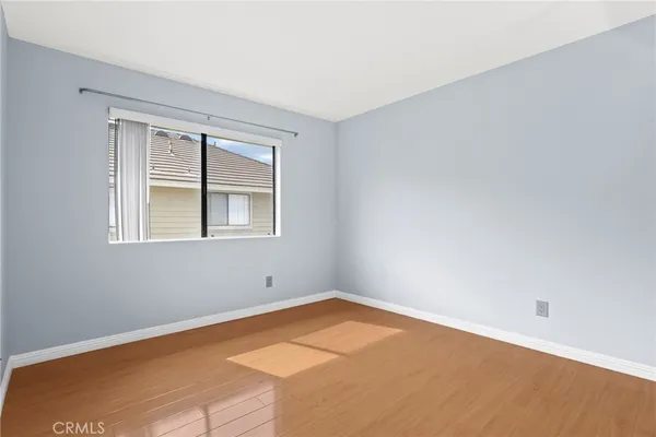a view of an empty room with window and wooden floor