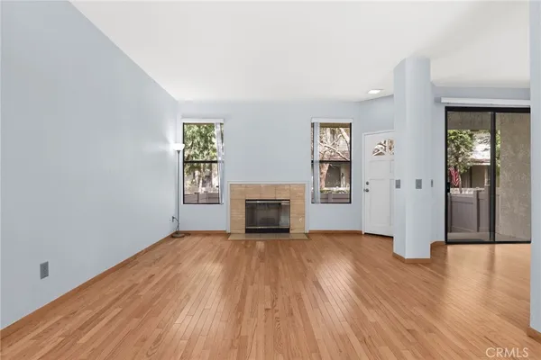 an empty room with wooden floor fireplace and windows