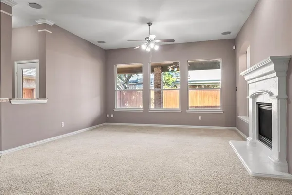 an empty room with chandelier fan and fireplace