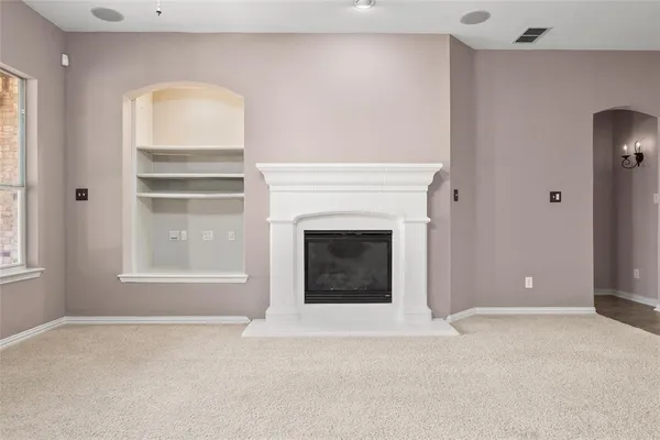 a view of an empty room with a fireplace and a window