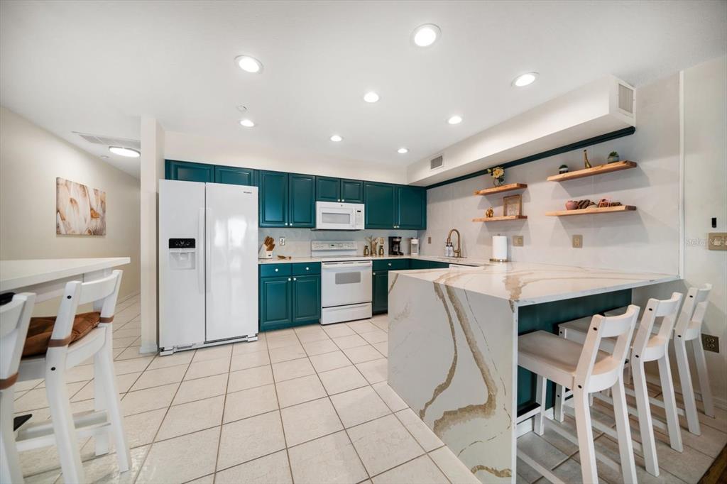 1500 Gulf Boulevard, Unit 103B Indian Rocks Beach, FL 33785 - Photo 11 of 58 a kitchen with stainless steel appliances granite countertop a refrigerator and microwave