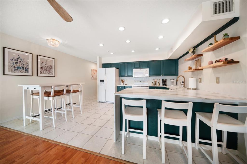 1500 Gulf Boulevard, Unit 103B Indian Rocks Beach, FL 33785 - Photo 12 of 58 a kitchen with stainless steel appliances kitchen island granite countertop a table chairs and a refrigerator