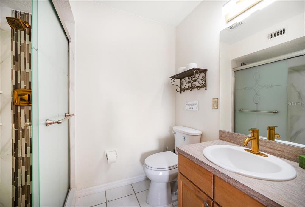 1500 Gulf Boulevard, Unit 103B Indian Rocks Beach, FL 33785 - Photo 17 of 58 a bathroom with a granite countertop sink a toilet and a mirror