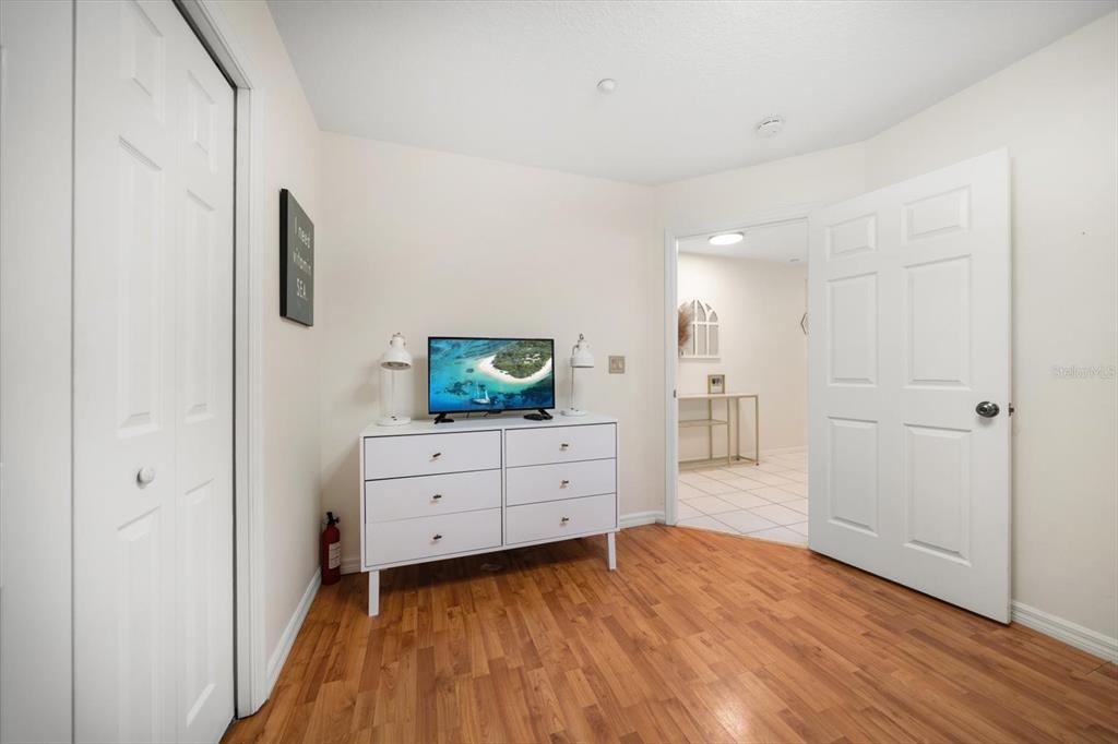 1500 Gulf Boulevard, Unit 103B Indian Rocks Beach, FL 33785 - Photo 22 of 58 a room with a white bed and a flat tv screen on dresser