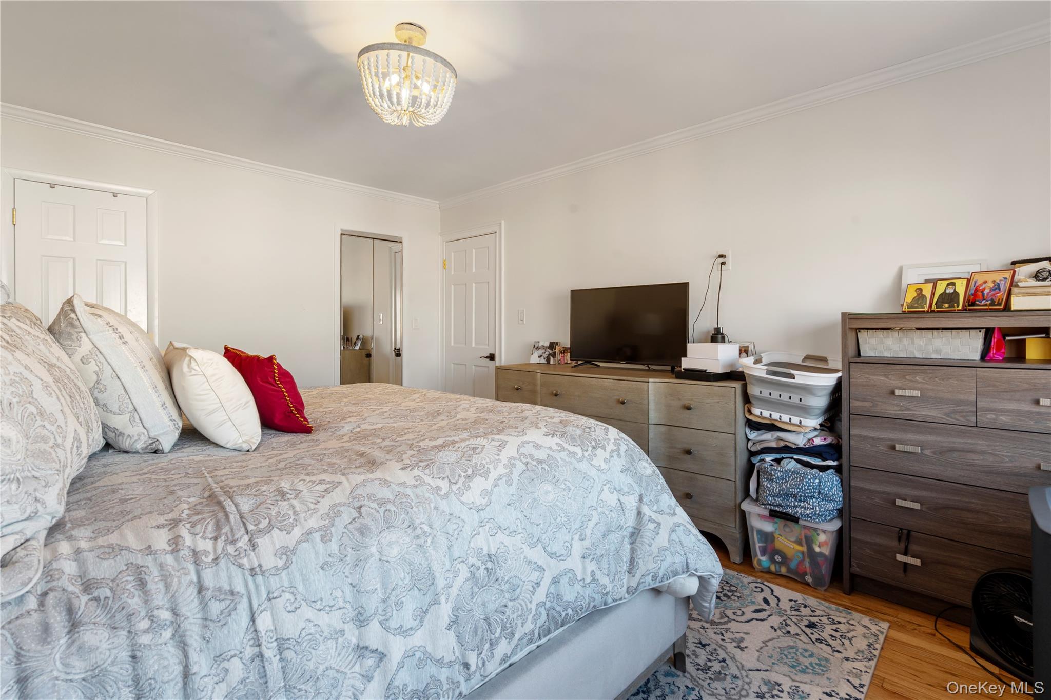 208-48 15th Road, Unit 2 Queens, NY 11360 - Photo 20 of 23 Bedroom featuring crown molding, wood finished floors, a chandelier, and multiple closets