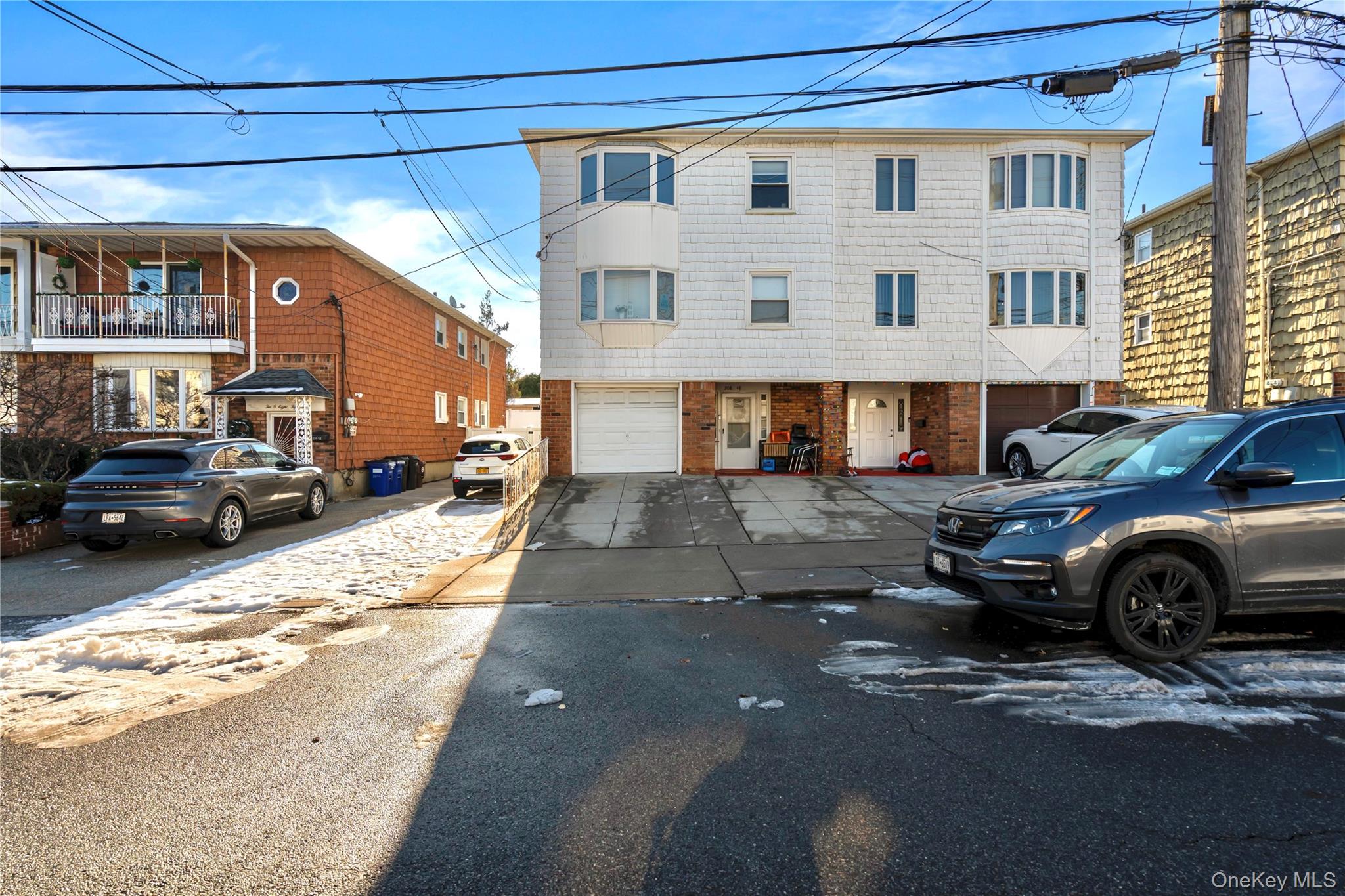 208-48 15th Road, Unit 2 Queens, NY 11360 - Photo 2 of 23 View of front facade with asphalt driveway and brick siding