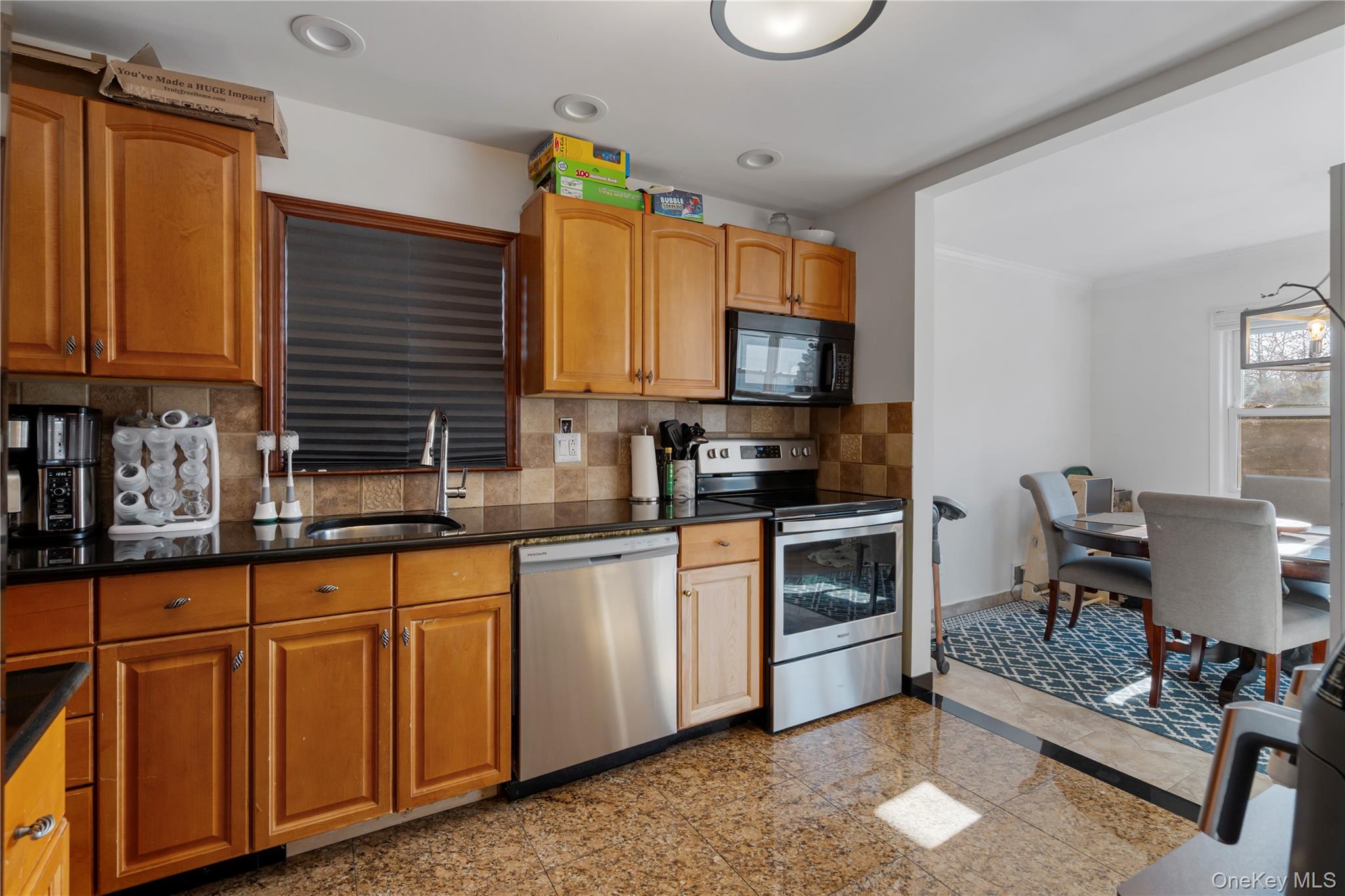 208-48 15th Road, Unit 2 Queens, NY 11360 - Photo 8 of 23 Kitchen with appliances with stainless steel finishes, granite tiled floors, tasteful backsplash, brown cabinets, and crown molding