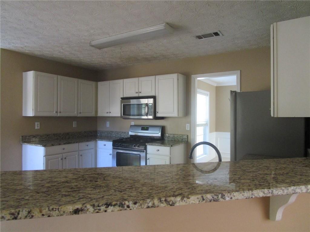 2825 Factor Walk Boulevard Suwanee, GA 30024 - Photo 12 of 25 a kitchen with stainless steel appliances granite countertop a stove sink and cabinets