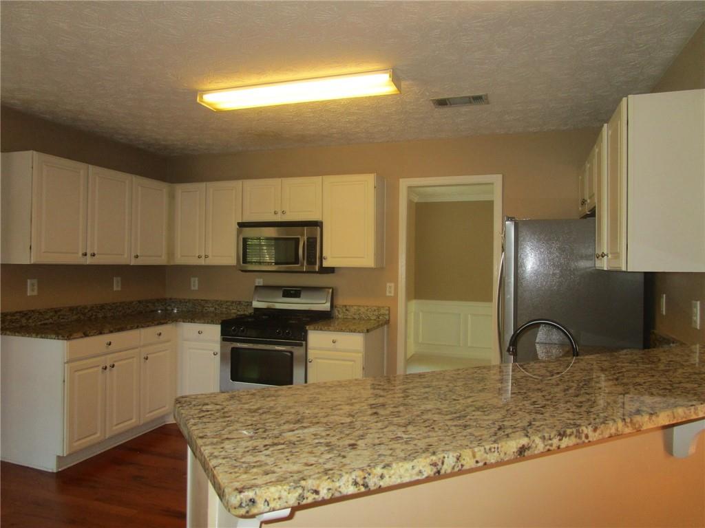 2825 Factor Walk Boulevard Suwanee, GA 30024 - Photo 9 of 25 a kitchen with stainless steel appliances granite countertop a sink stove and refrigerator