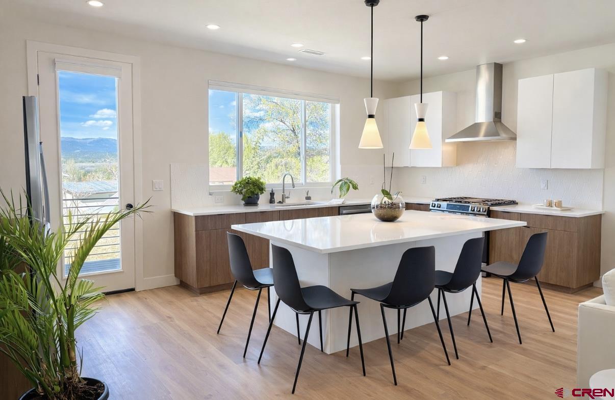 213 Treeline Street Durango, CO 81303 - Photo 9 of 41 a kitchen with stainless steel appliances granite countertop a stove a refrigerator a sink a dining table and chairs with wooden floor