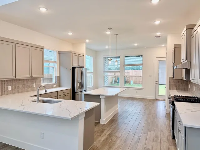 a kitchen with stainless steel appliances granite countertop a sink a stove a refrigerator cabinets and wooden floor