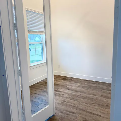 a view of an empty room with wooden floor and a window