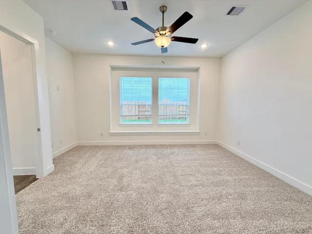 an empty room with window and ceiling fan