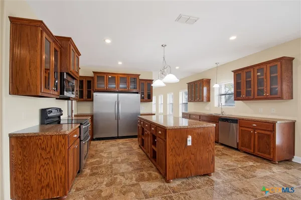 a kitchen with stainless steel appliances granite countertop a sink a stove and a refrigerator