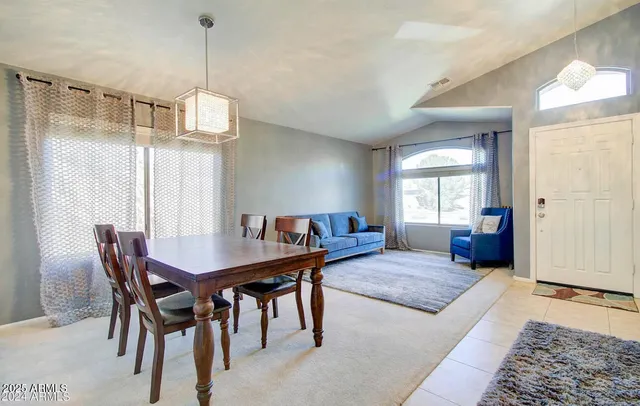 a view of a dining room and livingroom with furniture wooden floor a rug a potted plant and a chandelier