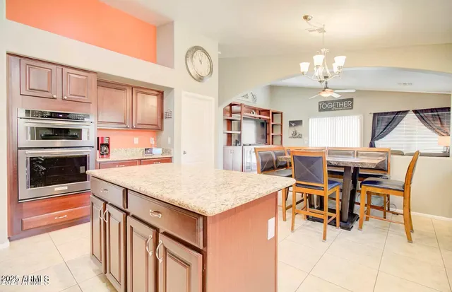 a open kitchen with stainless steel appliances kitchen island granite countertop a table chairs in it and wooden floors
