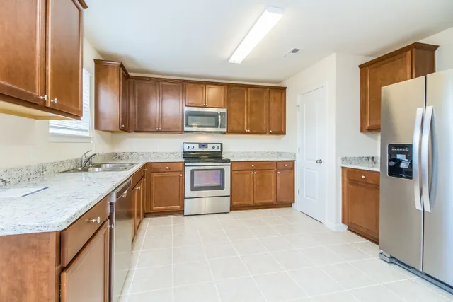 a kitchen with stainless steel appliances granite countertop a stove top oven a sink dishwasher a refrigerator and a microwave