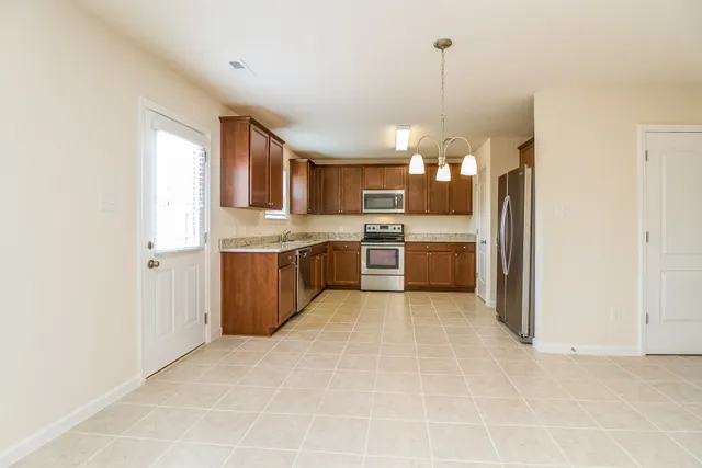 a kitchen with stainless steel appliances granite countertop a stove top oven a refrigerator and a sink