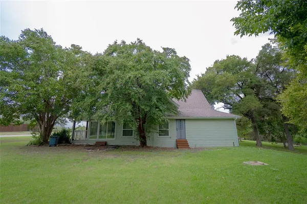 a view of a yard in front of a house with large tree