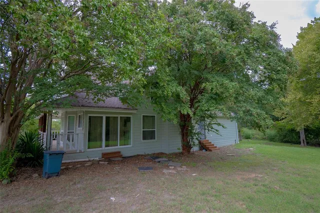 a view of a house with a yard and large tree