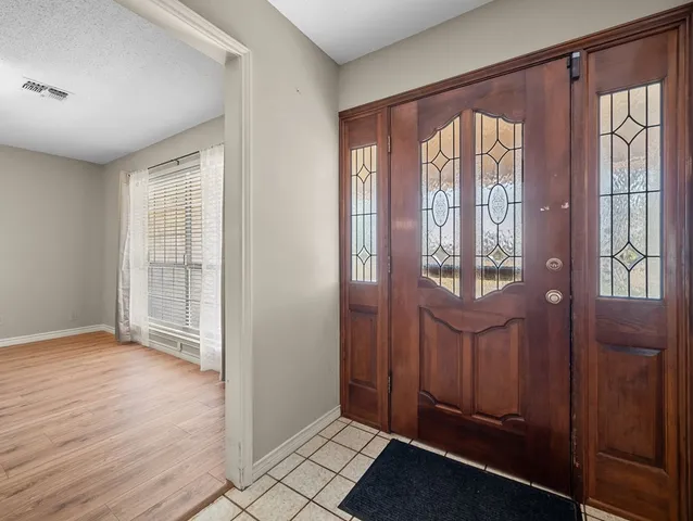 a view of an empty room with wooden floor and a fireplace