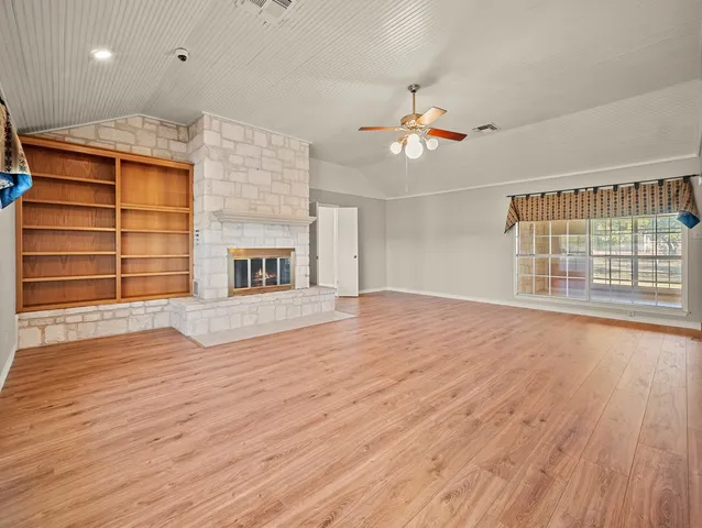 a view of an empty room with a window and wooden floor