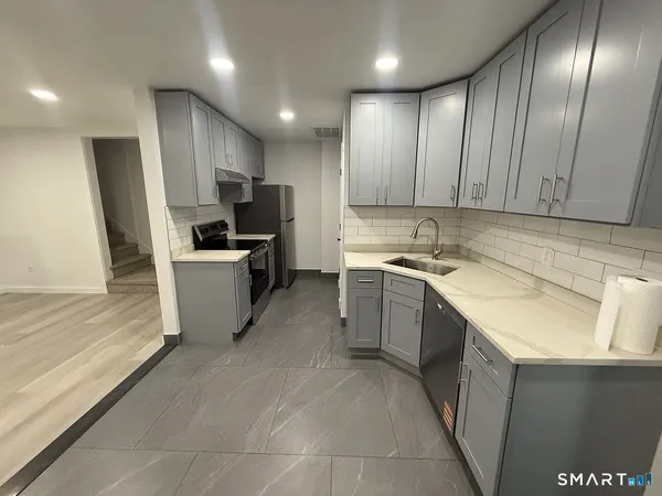 a kitchen with a sink stainless steel appliances a counter top space cabinets and a window