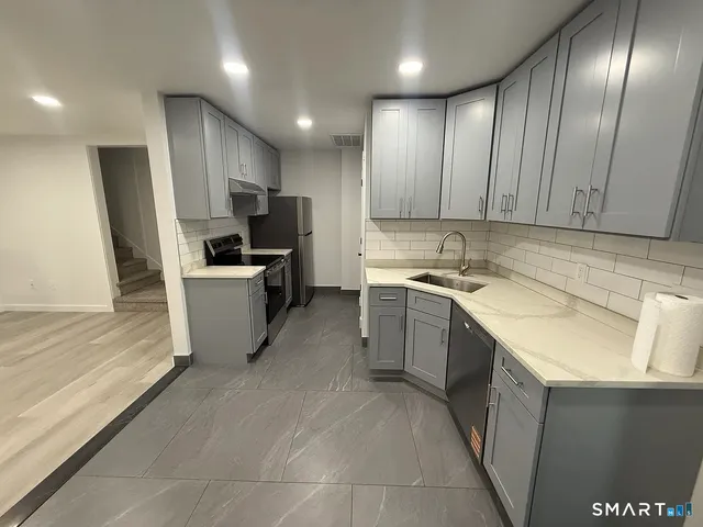 a kitchen with a sink stainless steel appliances a counter top space cabinets and a window