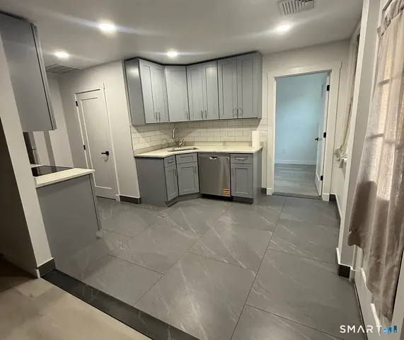 a large kitchen with a sink a refrigerator and cabinets