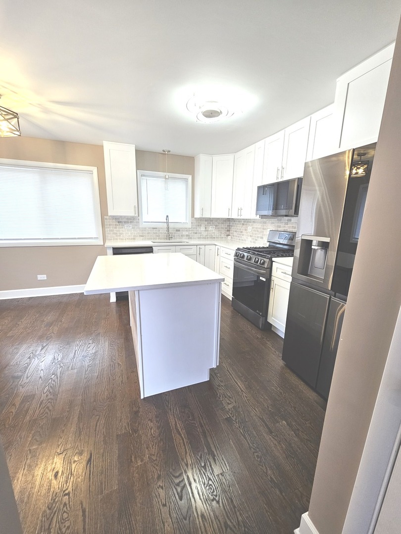 14926 Kenton Avenue Midlothian, IL 60445 - Photo 8 of 20 a kitchen with stainless steel appliances a refrigerator a sink a stove a microwave with wooden floors and cabinets