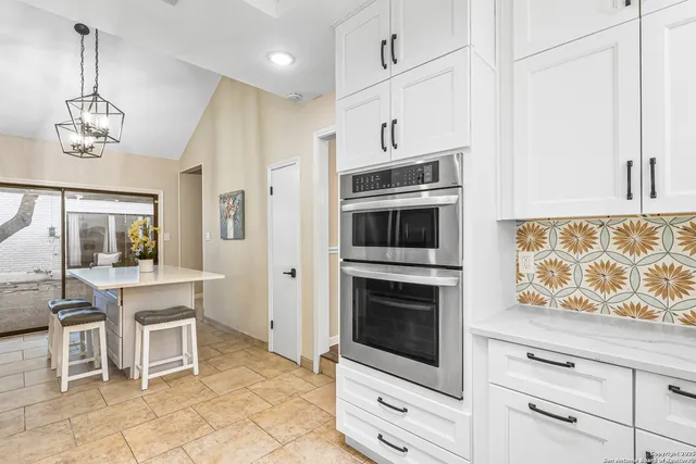 a kitchen with stainless steel appliances kitchen island granite countertop a stove a sink and a refrigerator with white cabinets